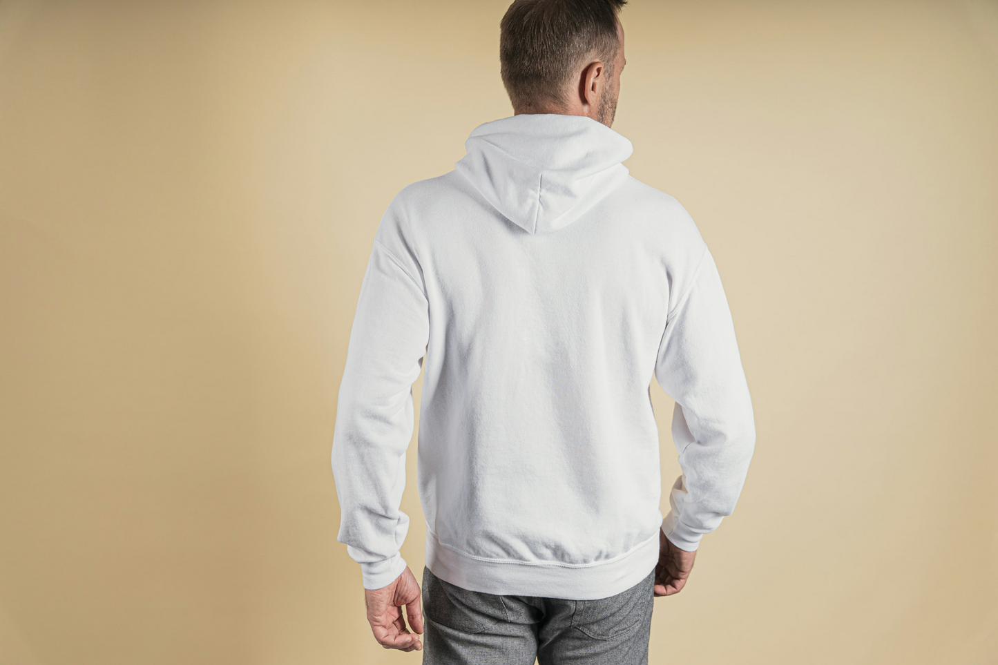 Man wearing a off white hoodie from behind on a beige background