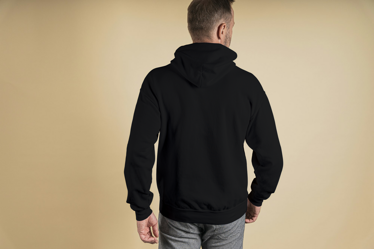 Person wearing a black hoodie from behind on a beige background