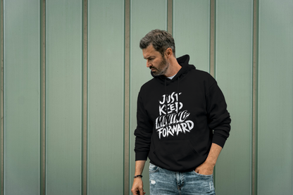 Man wearing a black hoodie with text, standing against a green wall.