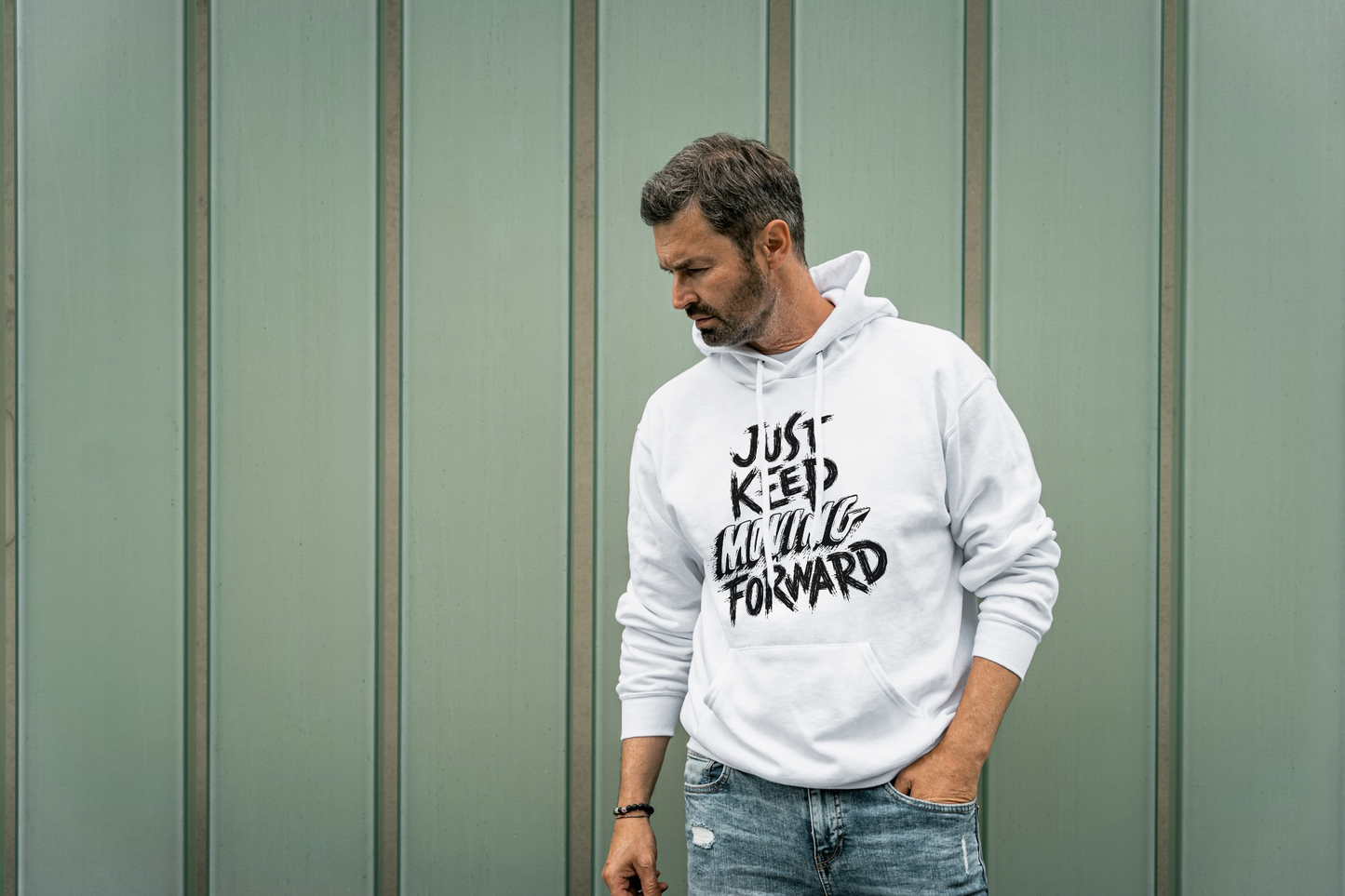 Man wearing a off white hoodie with text, standing against a green wall.