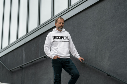 Man wearing a off white hoodie with 'DISCIPLINE' text, standing against a modern building.